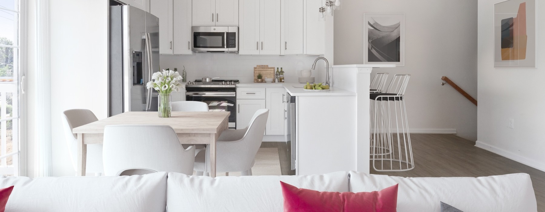 Model living room and kitchen at Cornerstone Hauppauge 55 and over apartments on Long Island, NY, featuring white couches.
