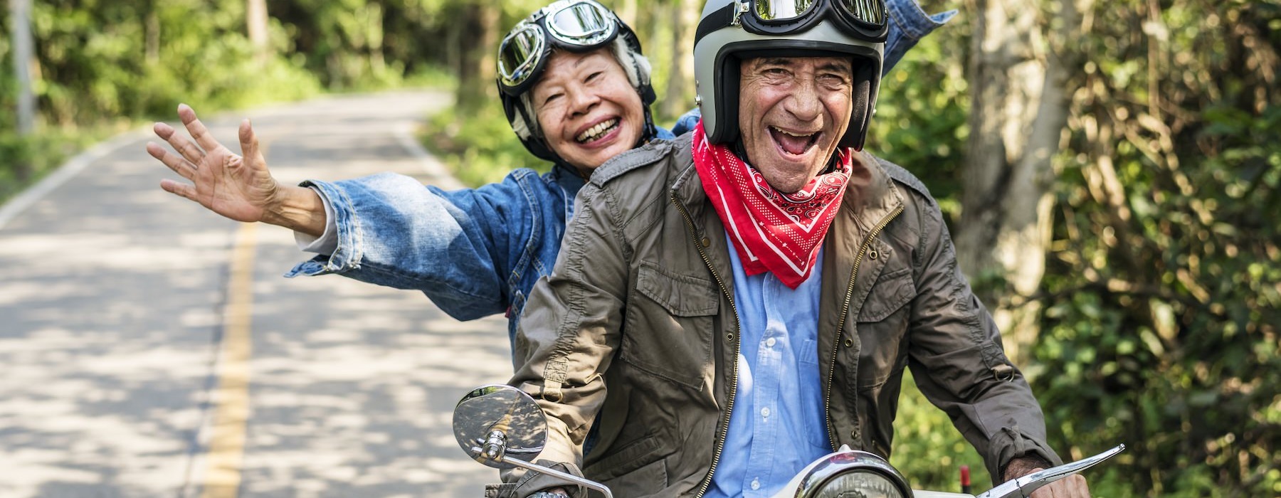 Two residents smiling and riding a moped at Cornerstone Hauppauge 55 and over apartments on Long Island, NY.
