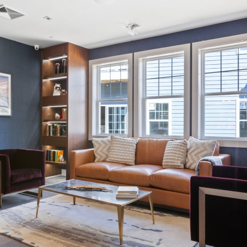 Clubhouse sitting area, in clubhouse, with couch, chairs, coffee table, bookshelves and large picture windows